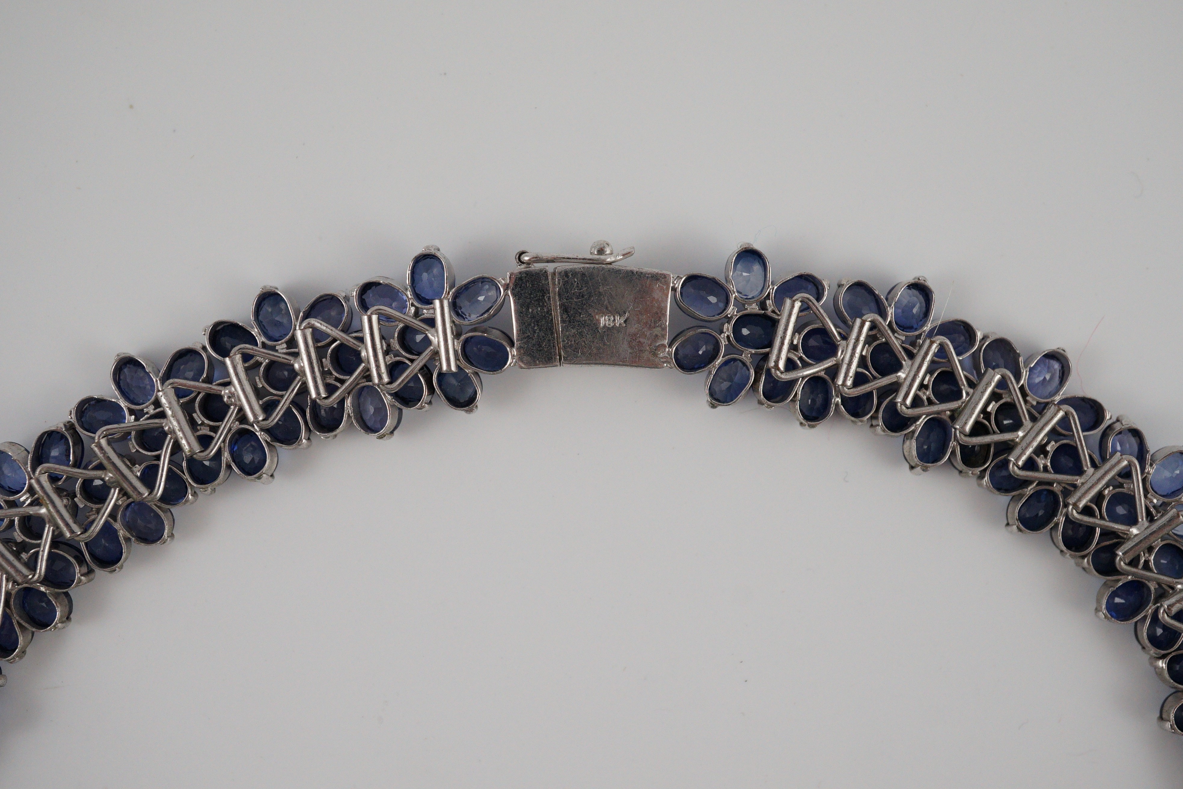 An 18K white gold and synthetic sapphire? flower head cluster set necklace